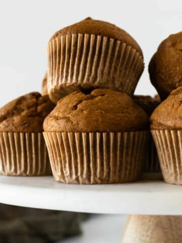 five pumpkin muffins on a cake stand.