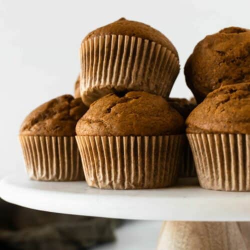 five pumpkin muffins on a cake stand.