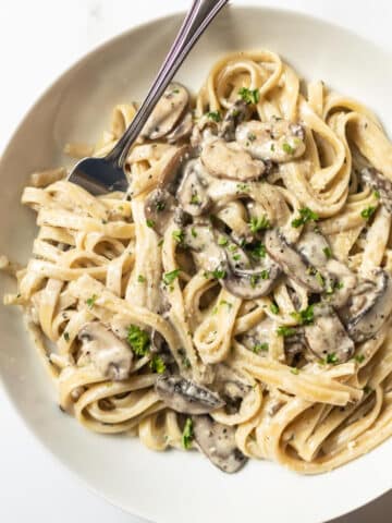 mushroom pasta with twirled on a fork in a white bowl.