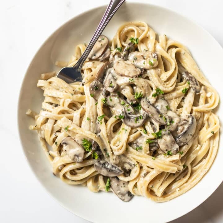 mushroom pasta with twirled on a fork in a white bowl.