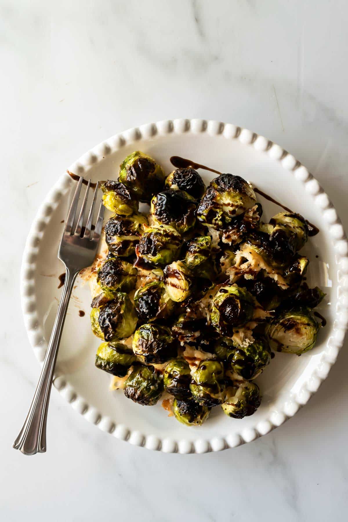 roasted brussels sprouts with balsamic glaze on a plate with a fork.