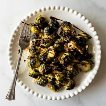 roasted brussels sprouts with a balsamic glaze drizzle on a plate with a fork.