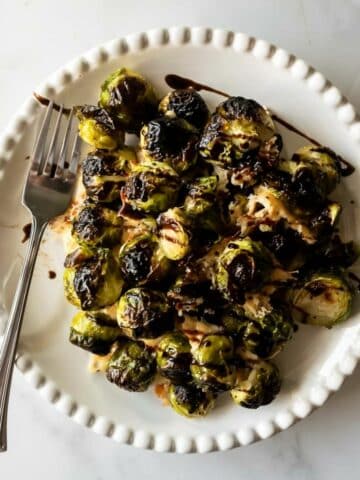 roasted brussels sprouts with a balsamic glaze drizzle on a plate with a fork.