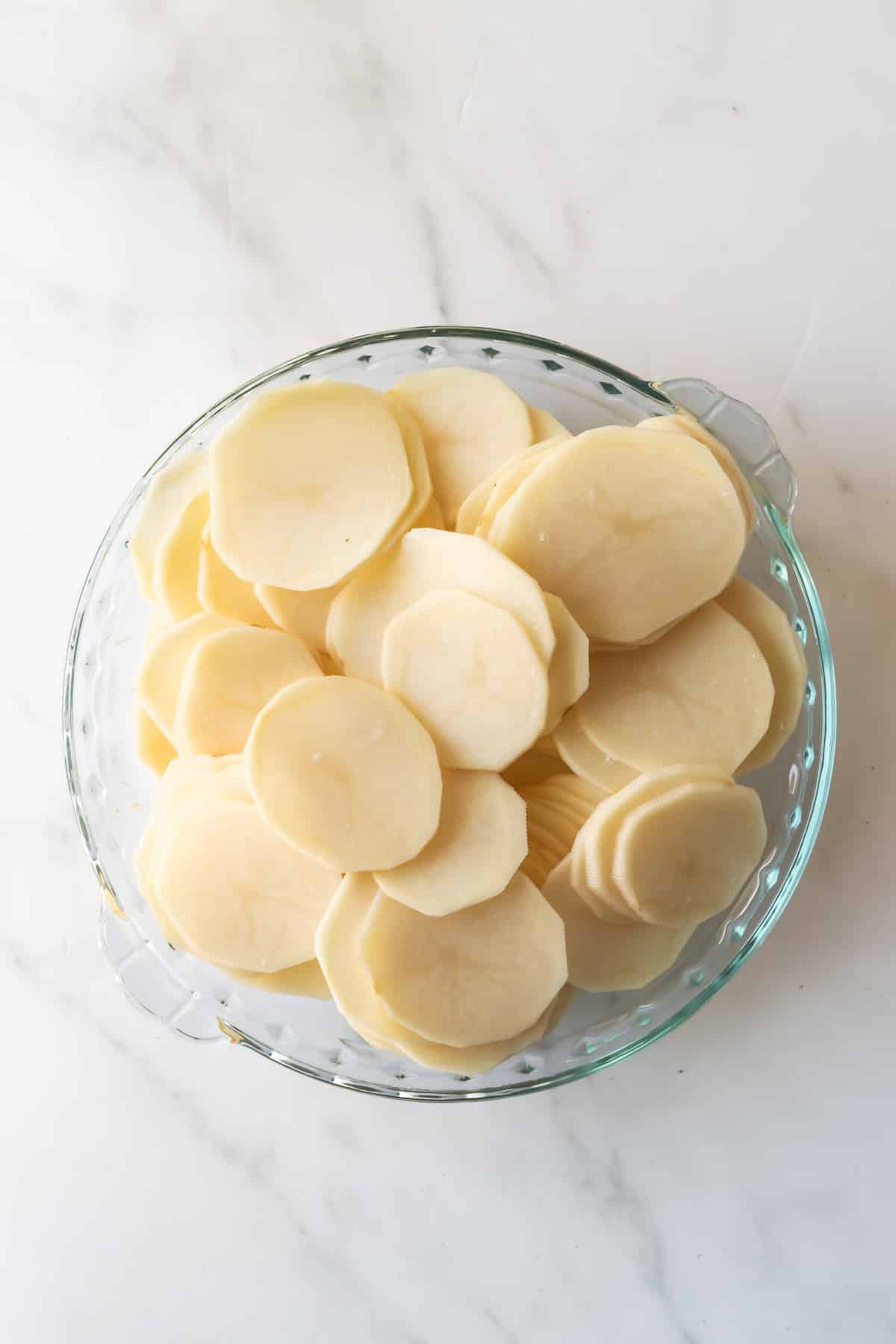 sliced potatoes in a glass pie dish.