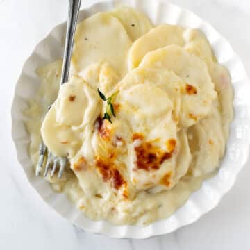 scalloped potatoes on a plate with a fork.