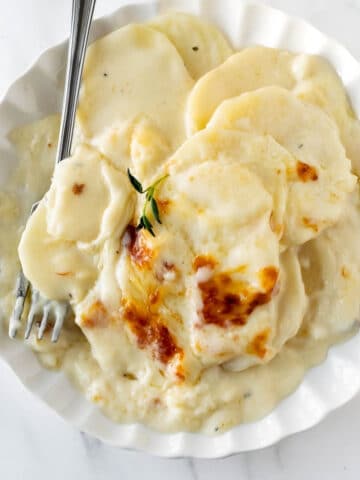 scalloped potatoes on a plate with a fork.