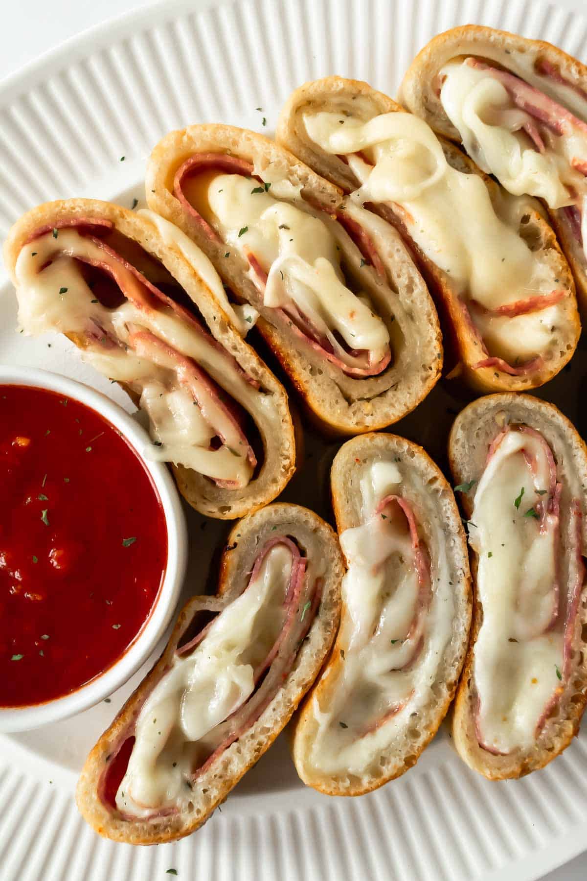 sliced stromboli on a white plate with marinara sauce.