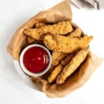 baked chicken tenders in a bowl with ketchup.