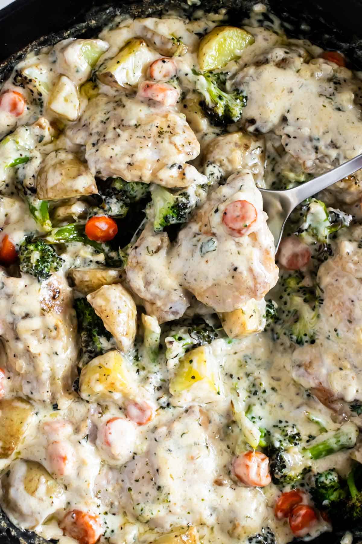 creamy garlic chicken in a skillet with a spoon.