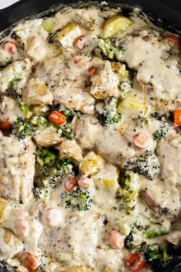 creamy garlic chicken and vegetables with a cream sauce in a skillet.