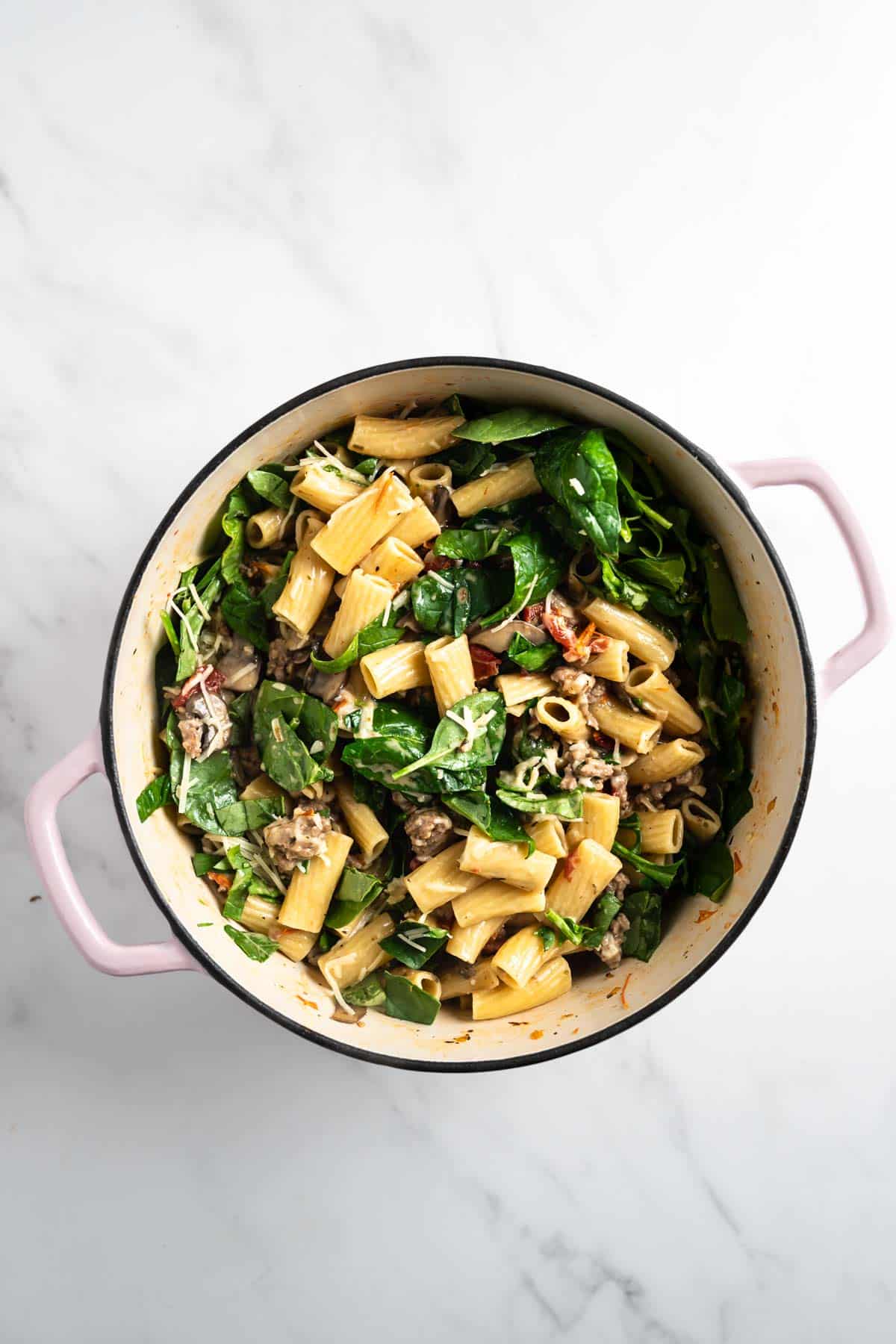 pasta with sausage and spinach in a pot.