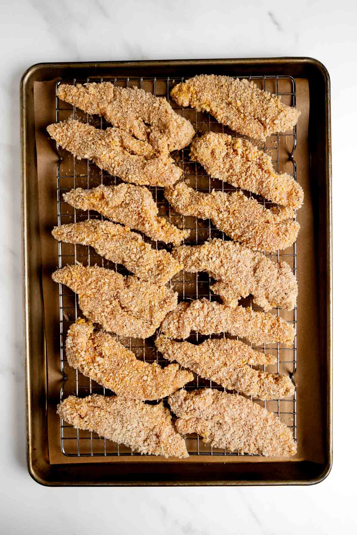 unbaked chicken tenders on a baking sheet.