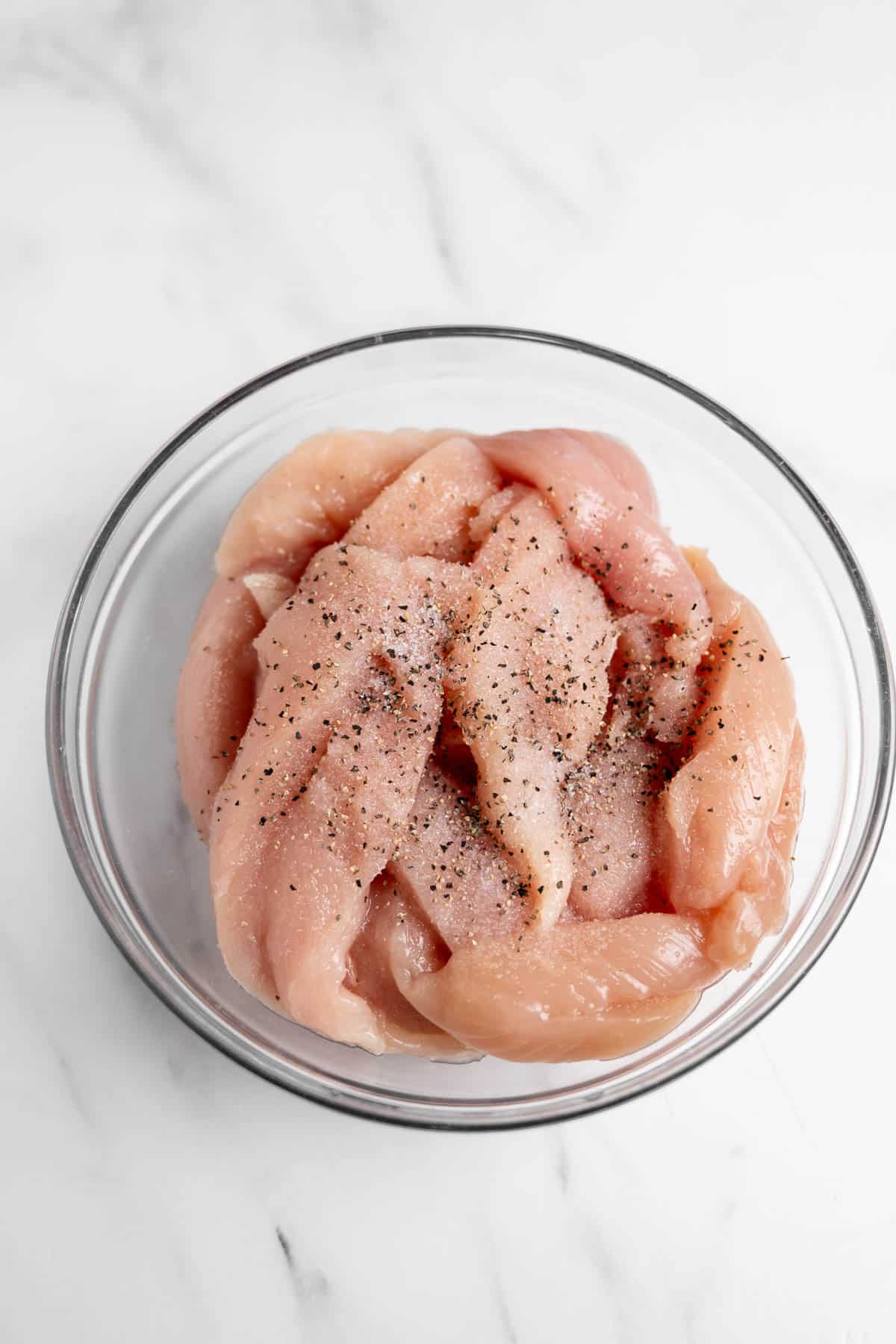 chicken tenders in a bowl with salt and pepper.