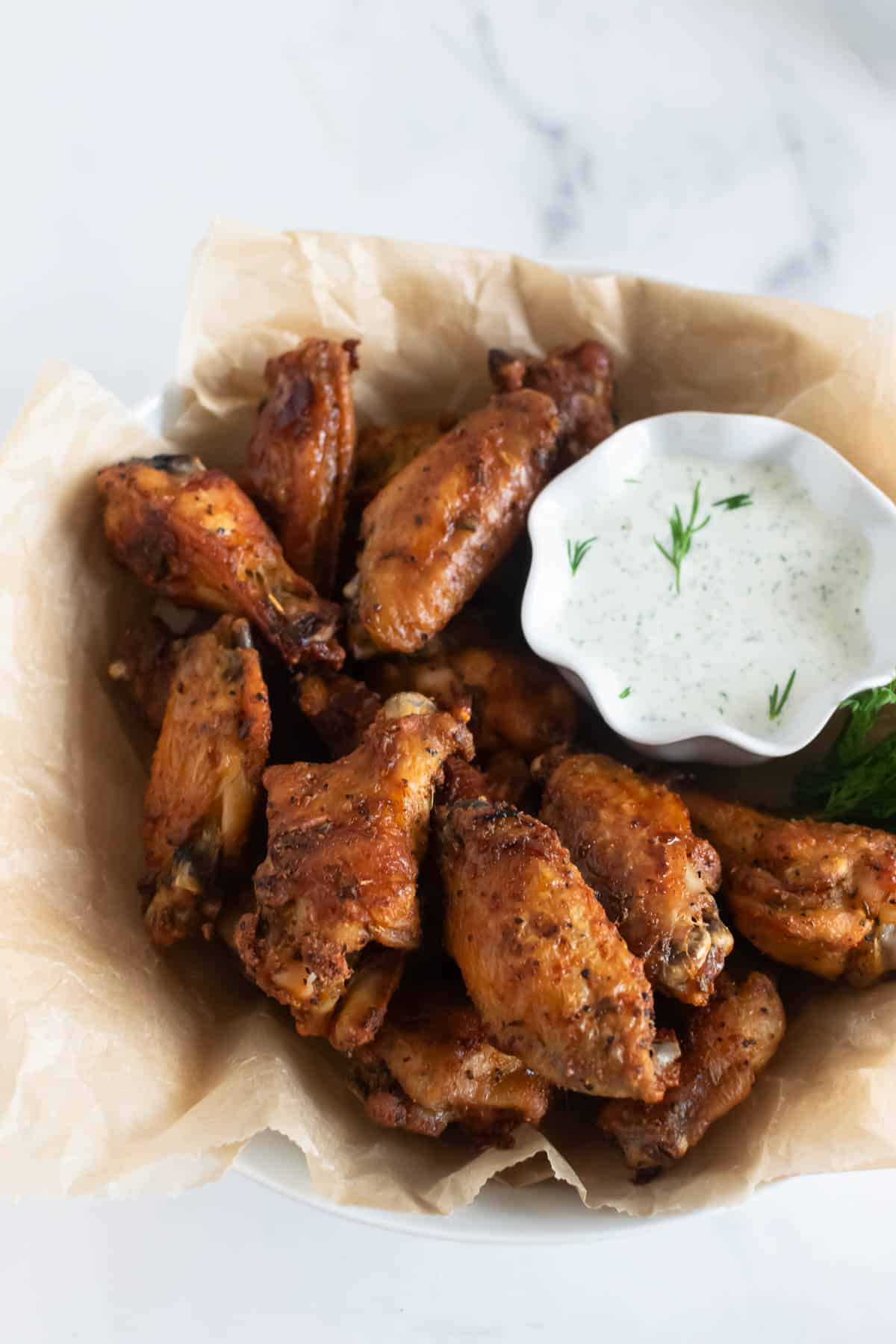 crispy baked chicken wings in a bowl with ranch dressing.