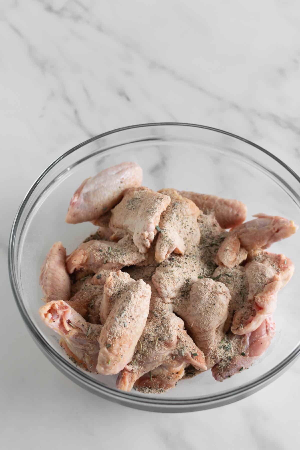 dry rub mixture on top of chicken wings in a bowl.