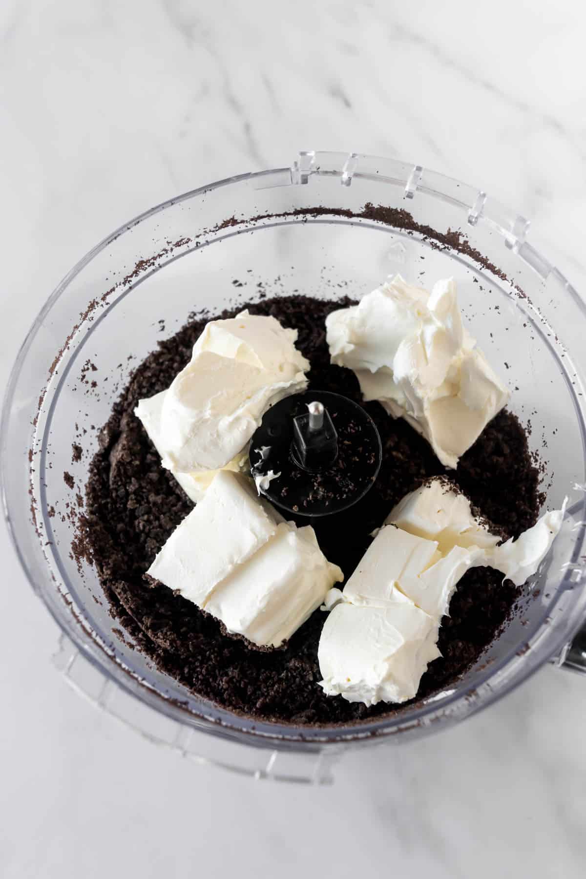 Oreo crumbs and cream cheese in a food processor.