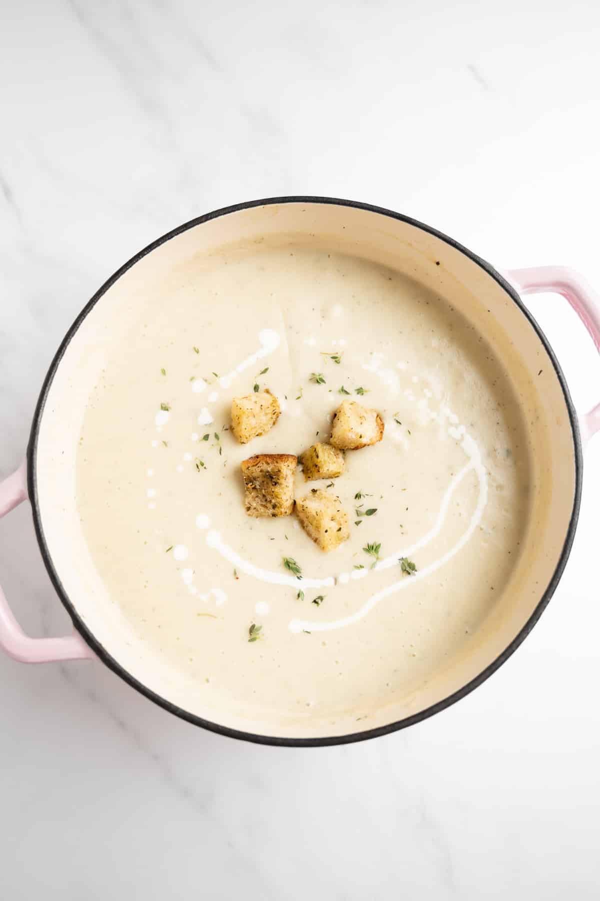 potato cauliflower soup in a large pot topped with croutons.