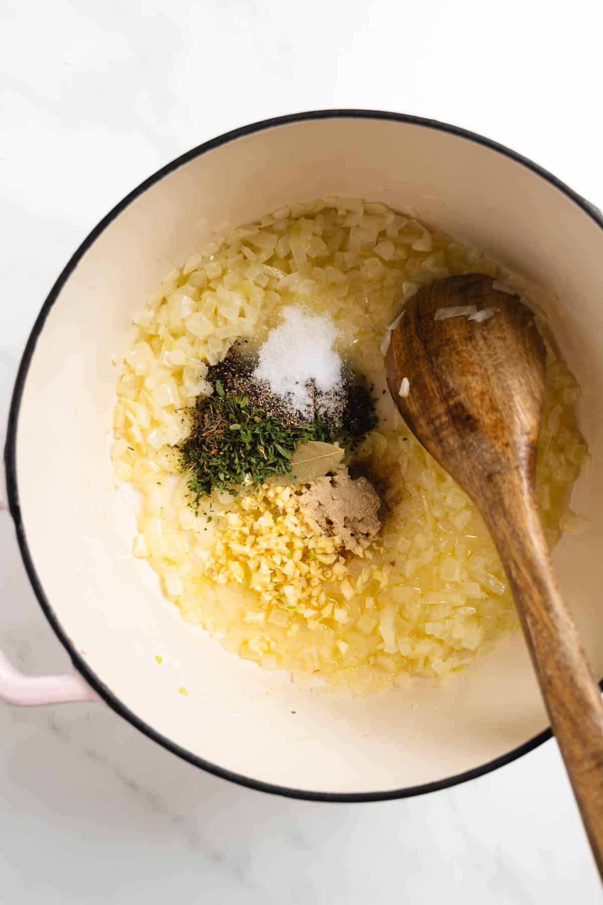 onions with spices in a large pot with a wooden spoon.