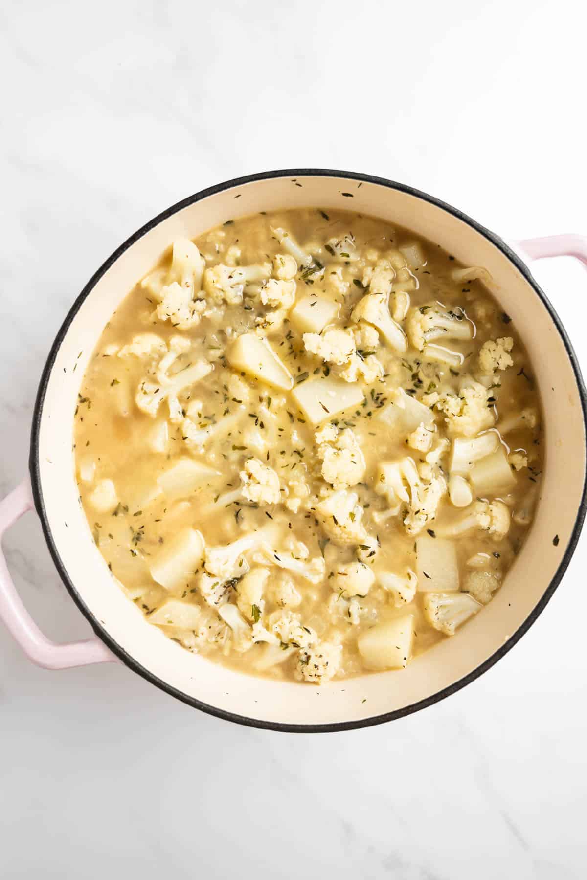 chopped potatoes and cauliflower florets in a bot with chicken broth.