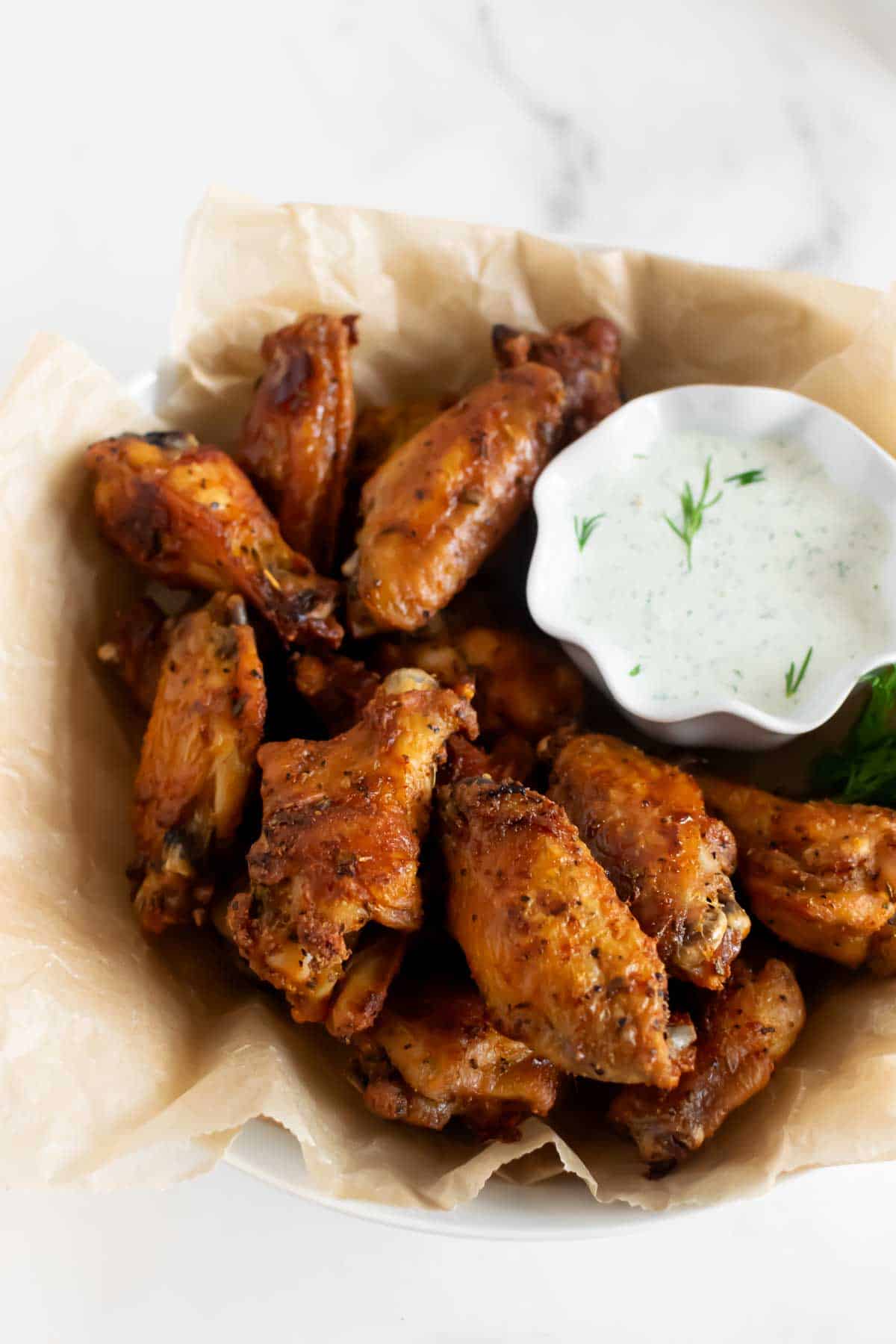 baked chicken wings in a bowl with ranch dressing.