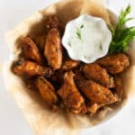 crispy baked chicken wings in a bowl with dressing.