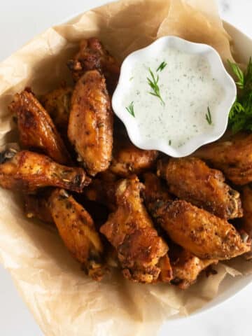 crispy baked chicken wings in a bowl with dressing.