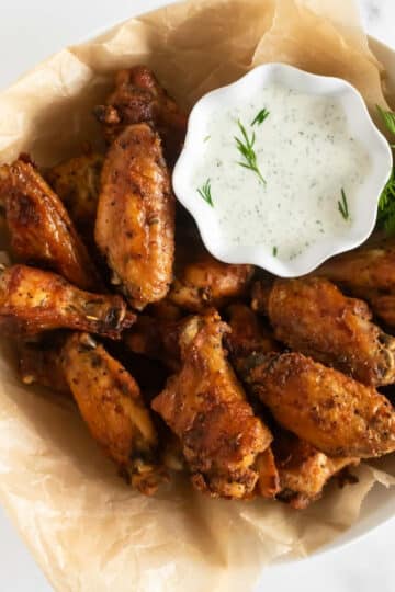 crispy baked chicken wings in a bowl with dressing.