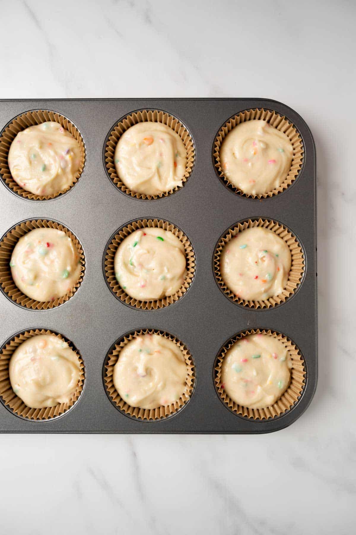 confetti cupcake batter in a muffin pan.