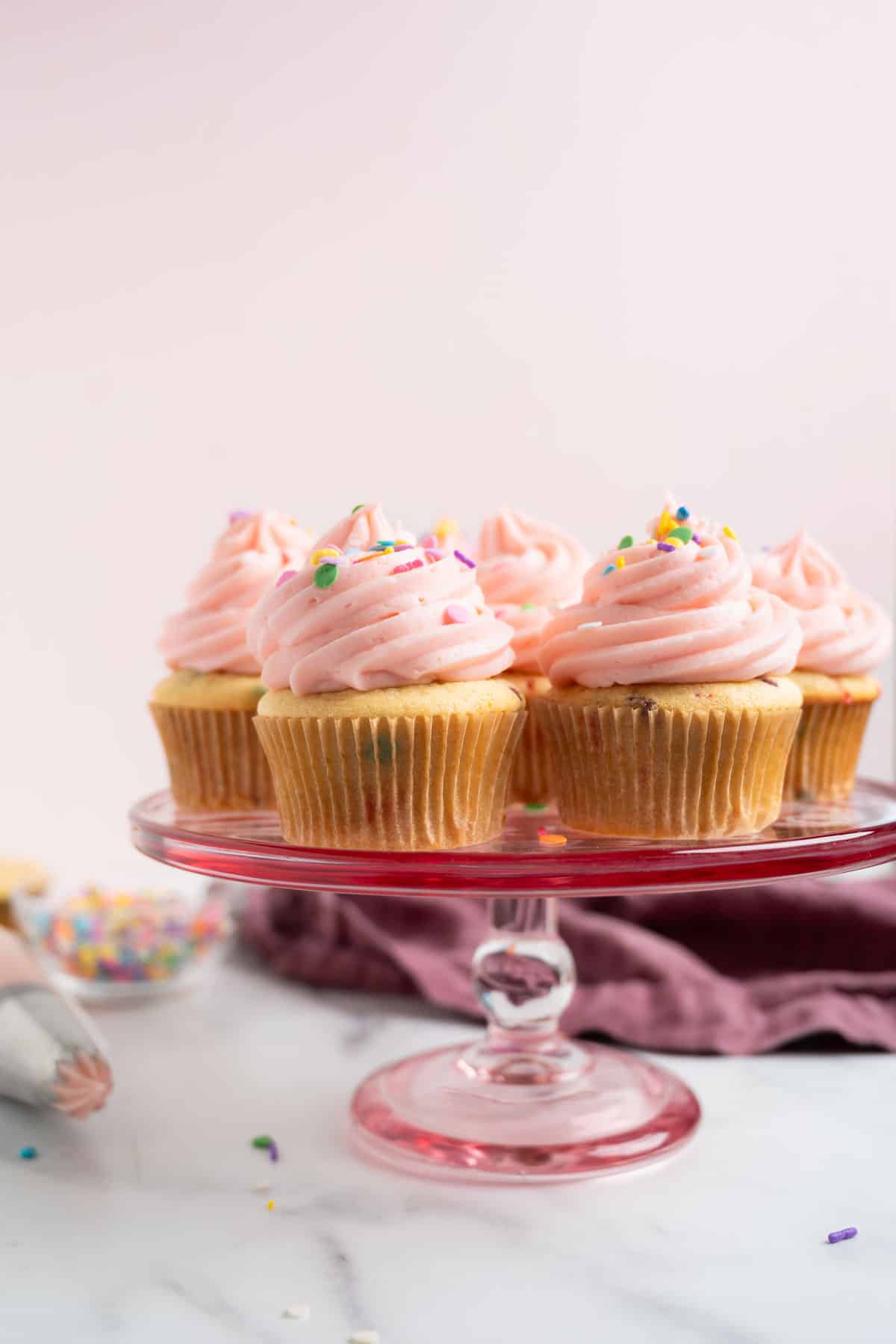 confetti cupcakes on a pink cake stand.