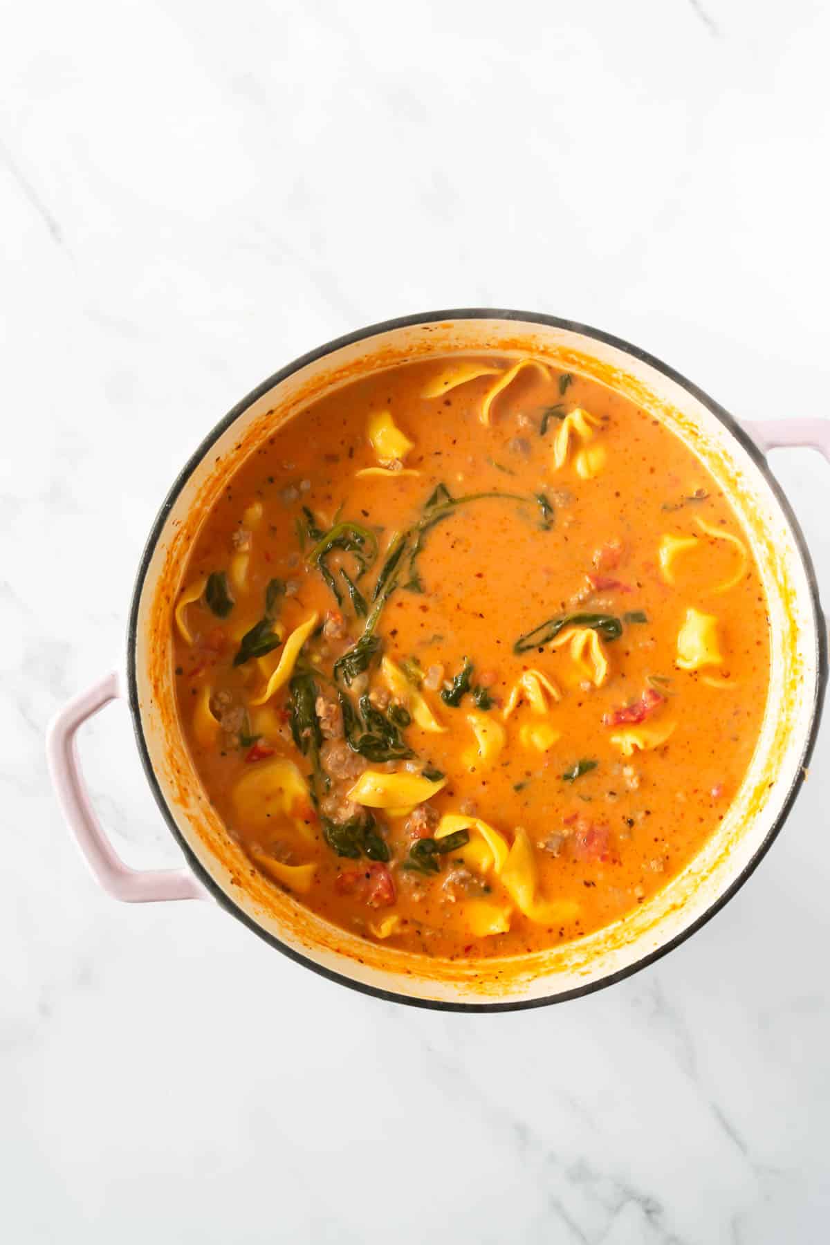 creamy tortellini soup with spinach in a dutch oven.