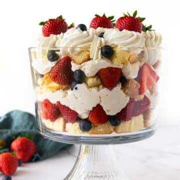 berries and whipped cream with cake layered in a trifle bowl.