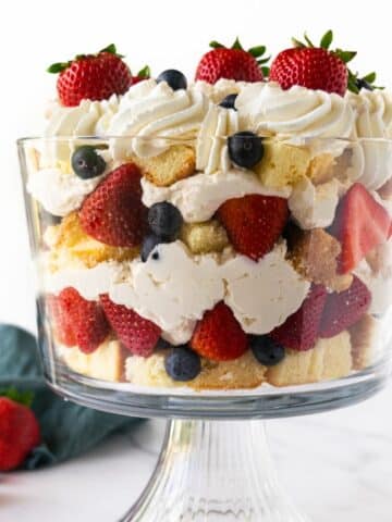 berries and whipped cream with cake layered in a trifle bowl.