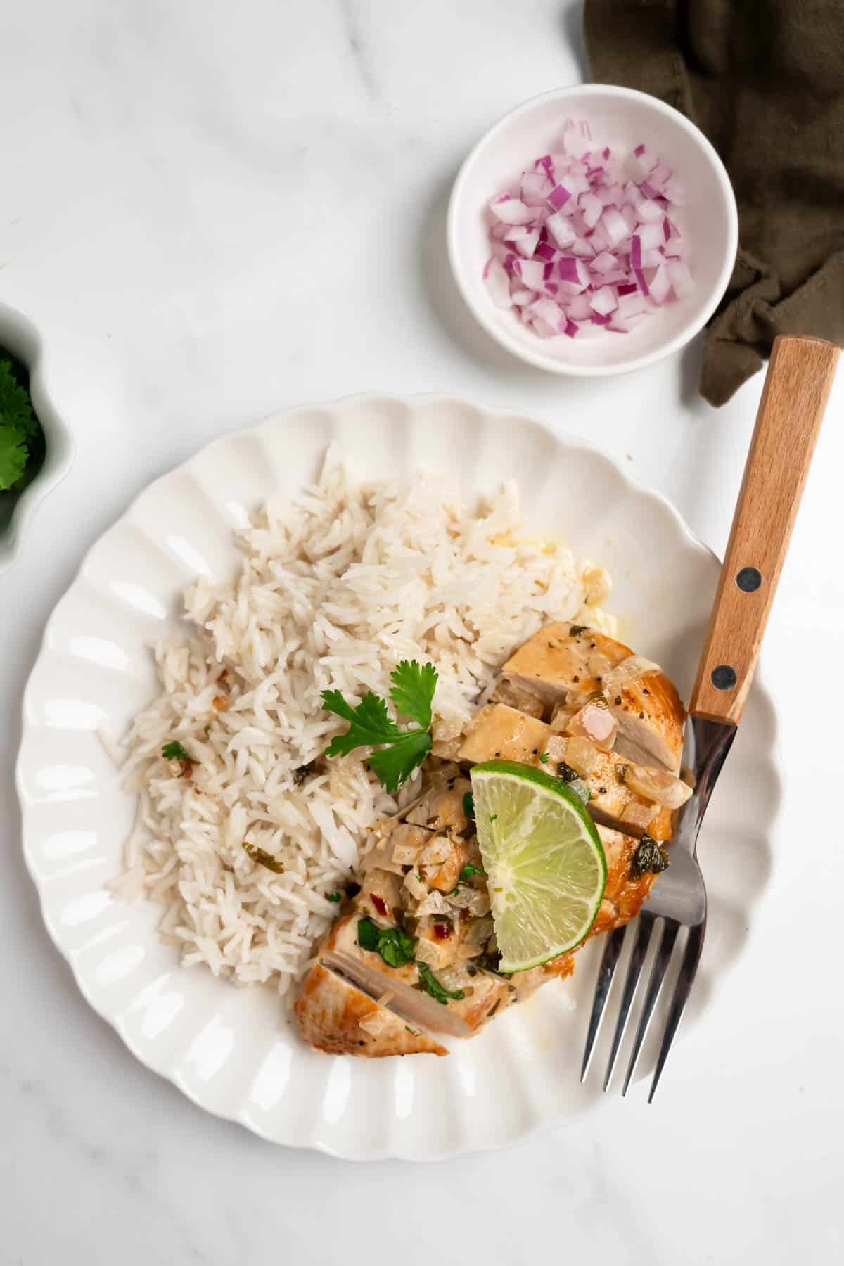 sliced cilantro lime chicken with a creamy sauce with rice on a plate with a fork.