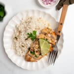 sliced cilantro lime chicken with a cream sauce with rice on a plate with a fork.