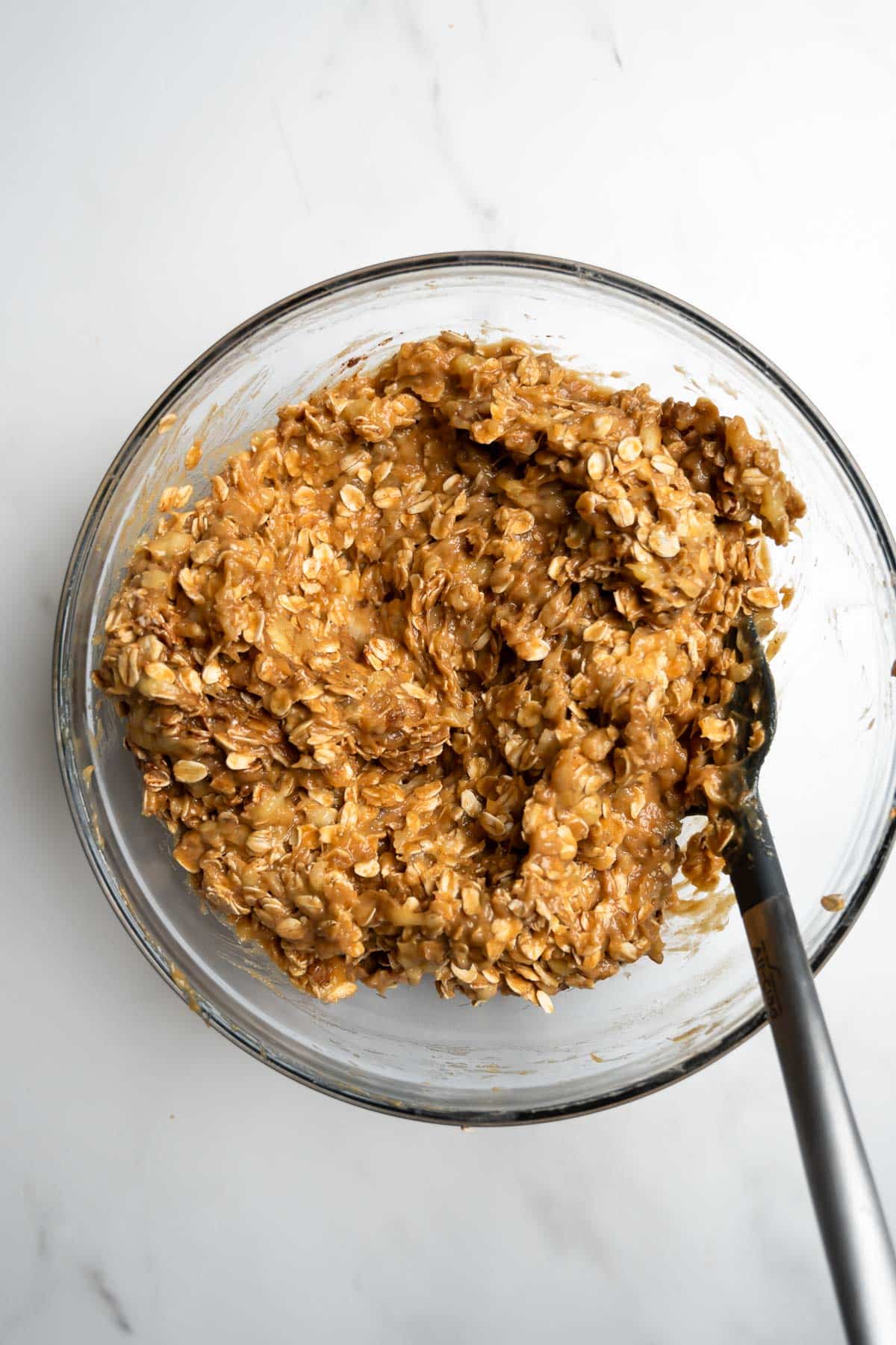 cookie dough in a glass mixing bowl with a spatula.