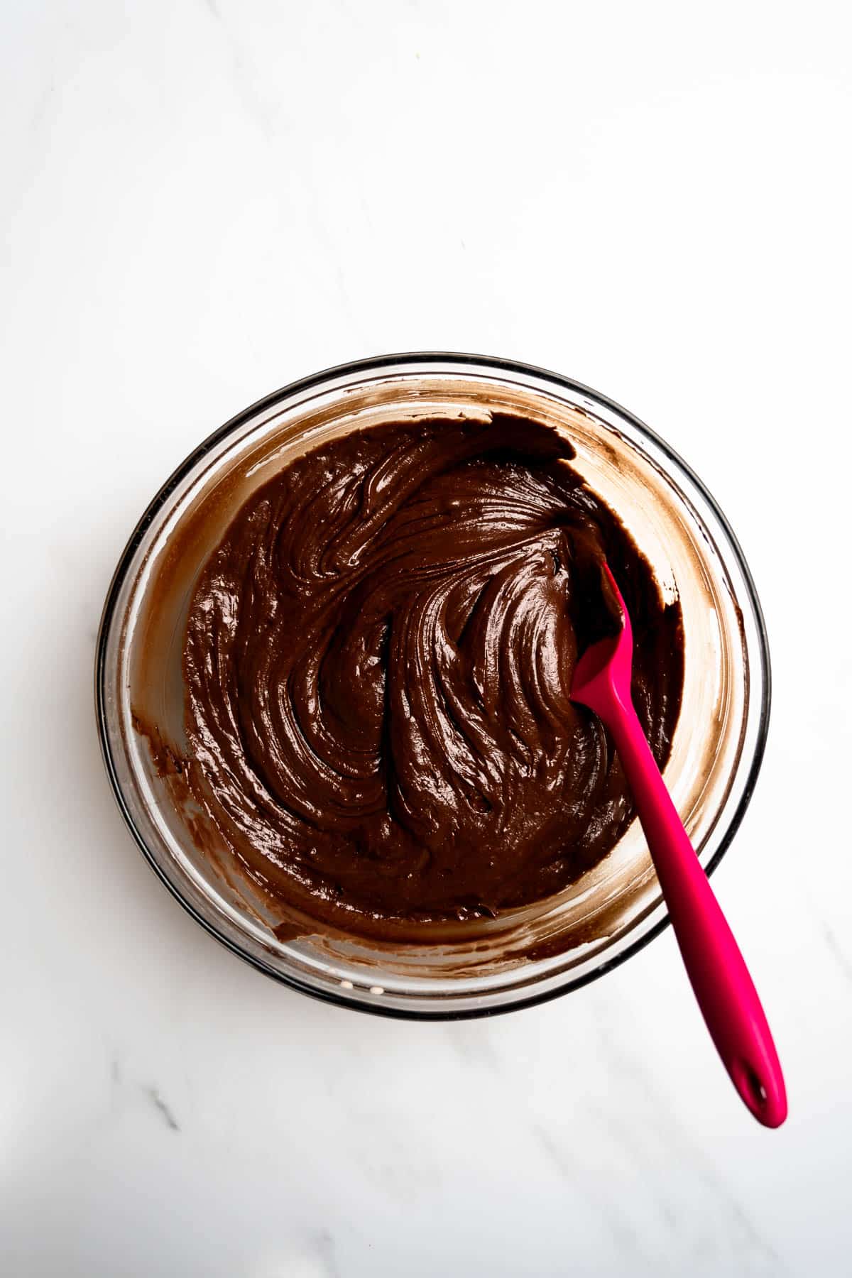 chocolate cake batter whisked together in a bowl with spatula.