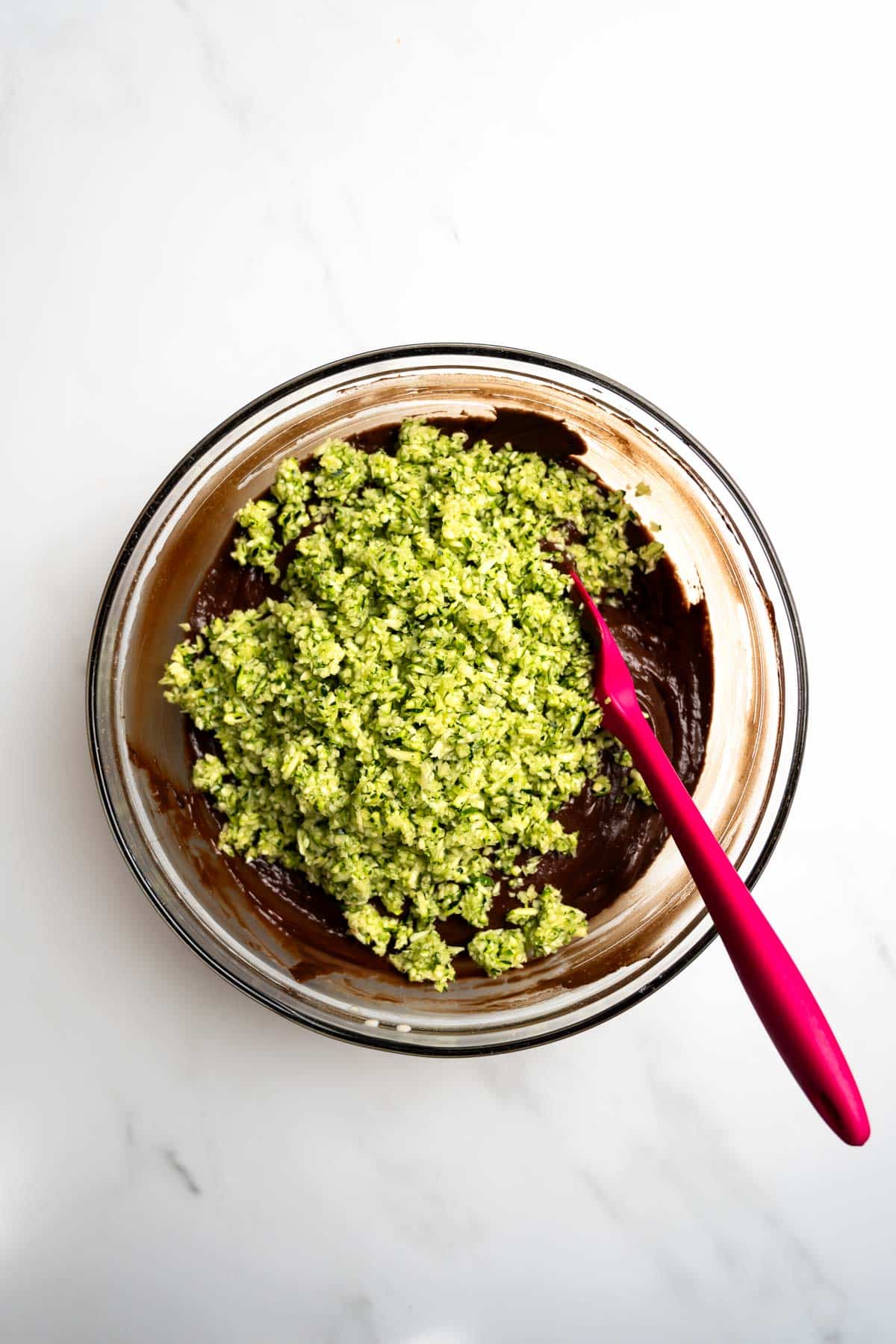 chocolate cake batter topped with shredded zucchini in a bowl.