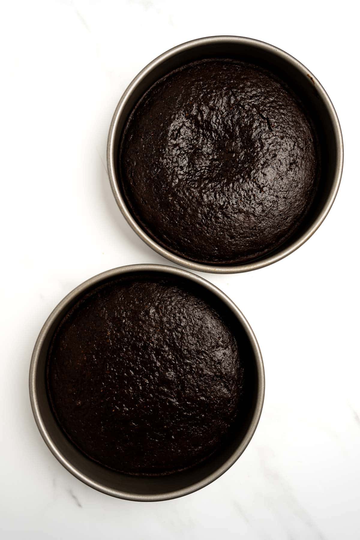baked chocolate cake batter in two round cake pans.