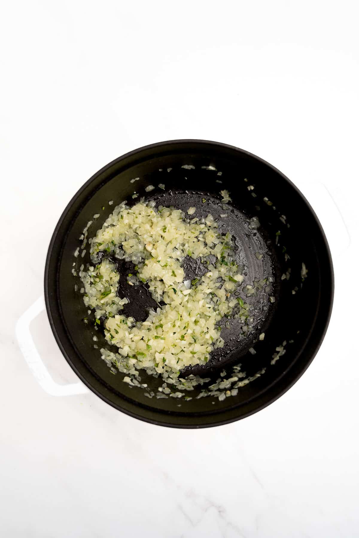 onions and spices in a black pot.