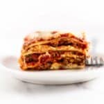 slice of lasagna on a white plate with a fork.