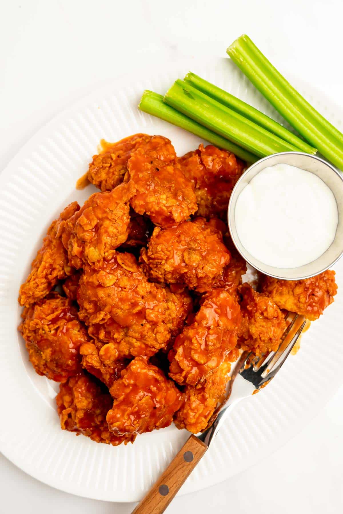 boneless buffalo bites on a platter with celery and blue cheese.