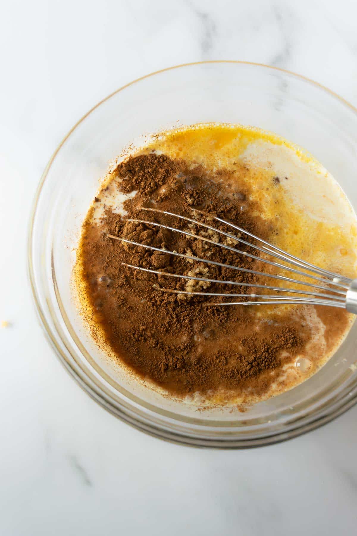 we ingredients with cinnamon in a glass bowl with whisk.