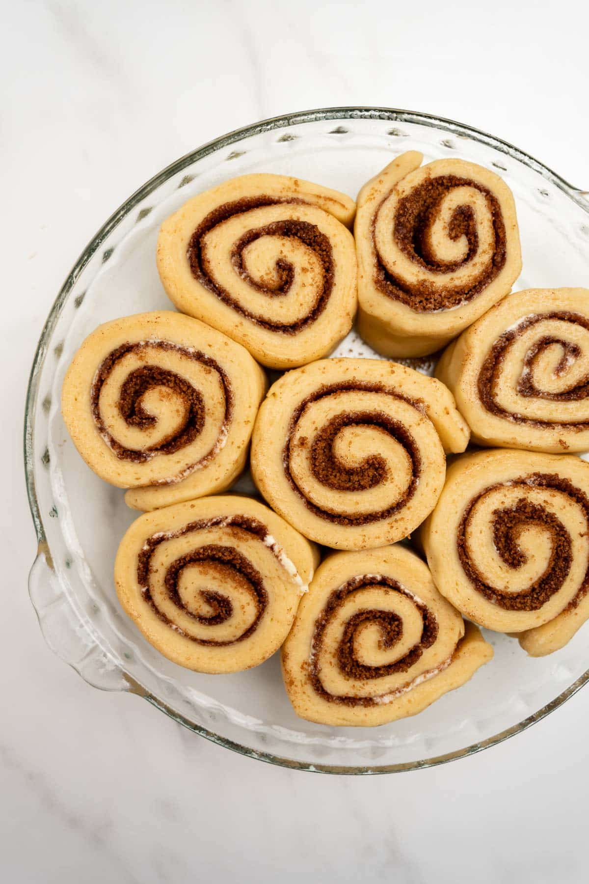 puffed up cinnamon rolls in a round baking dish.