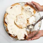 homemade cinnamon rolls in a round baking pan with spoon.