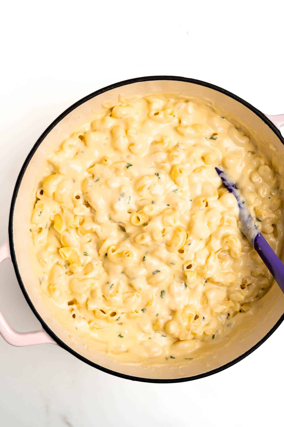mac and cheese in a pot with a purple spoon.