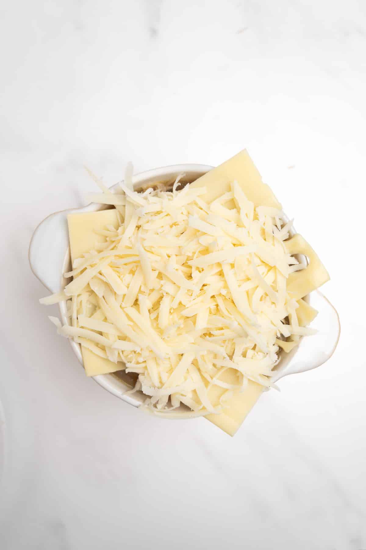 cheese on top French onion soup in a white bowl.