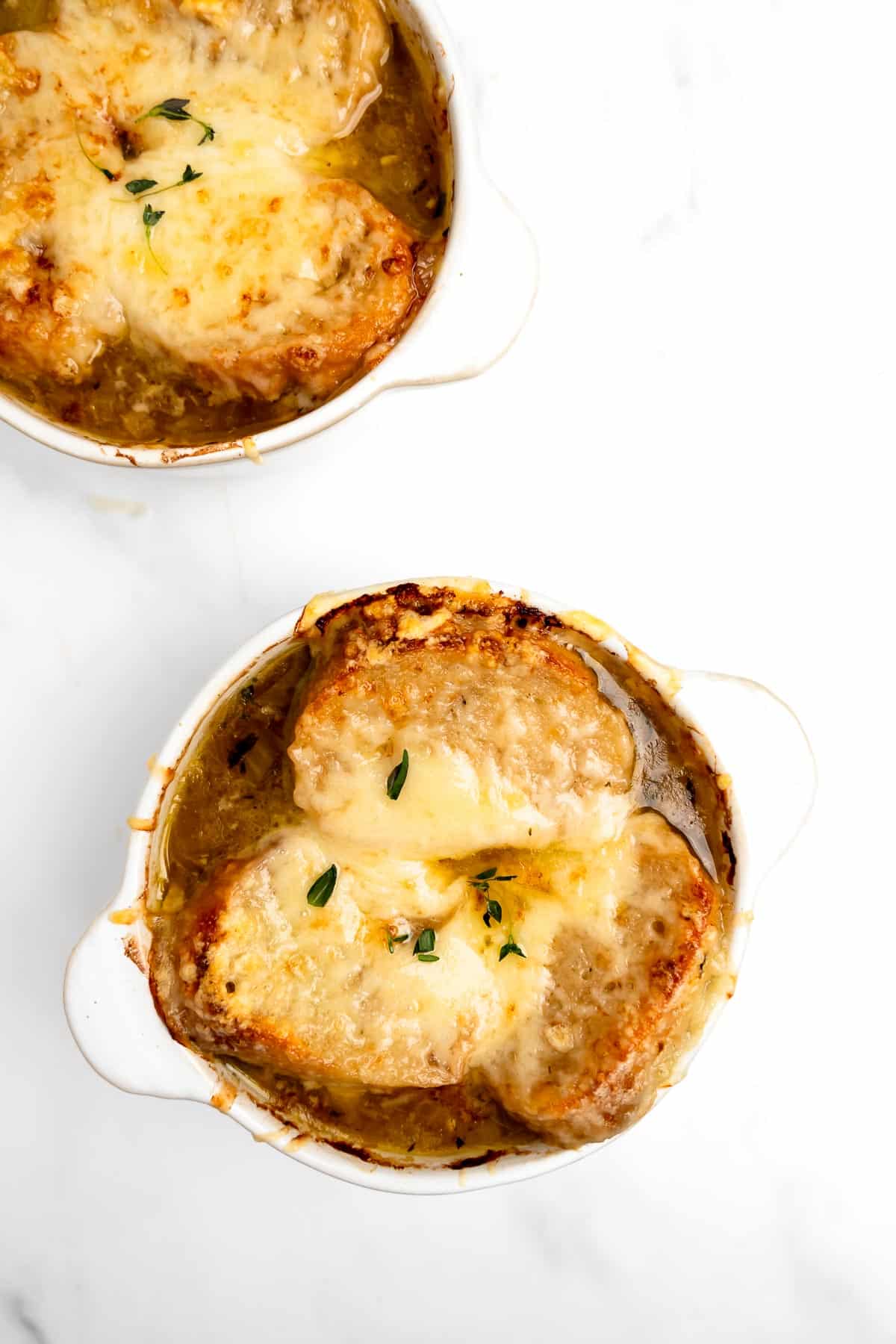 2 bowls of French onion soup with melted cheese.