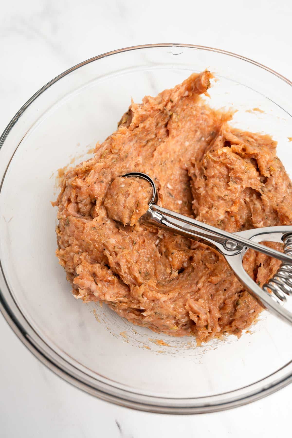 ground chicken with spices in a bowl with a spoon.