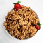 granola clusters in a bowl with strawberries.