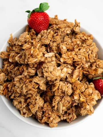 granola clusters in a bowl with strawberries.